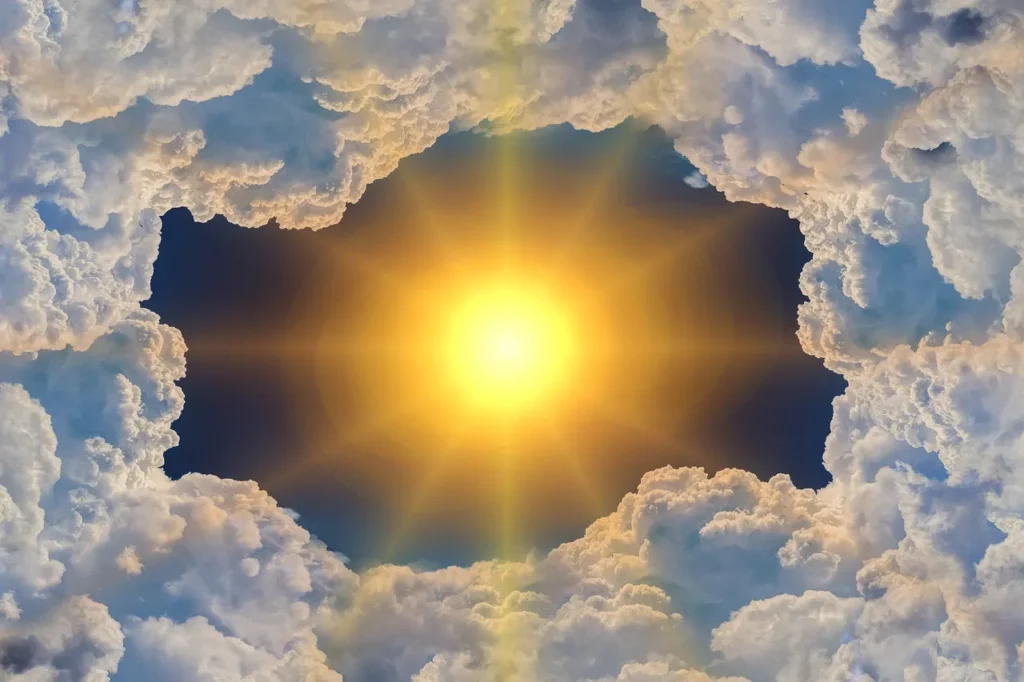 A bright, radiating sun at the center of a deep blue sky, framed by soft, fluffy white and golden-tinged clouds, creating a dramatic celestial opening.