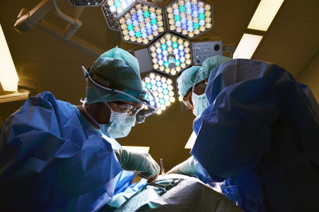 Two highly focused surgeons in blue scrubs, masks, and headlamps performing an operation under bright, geometric surgical lights, symbolizing the intensity and focus of specialist medical care.