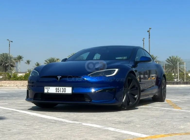 A deep blue luxury electric sedan parked in a sunlit paved parking lot, representing premium car rental options for travelers exploring Morocco by road.